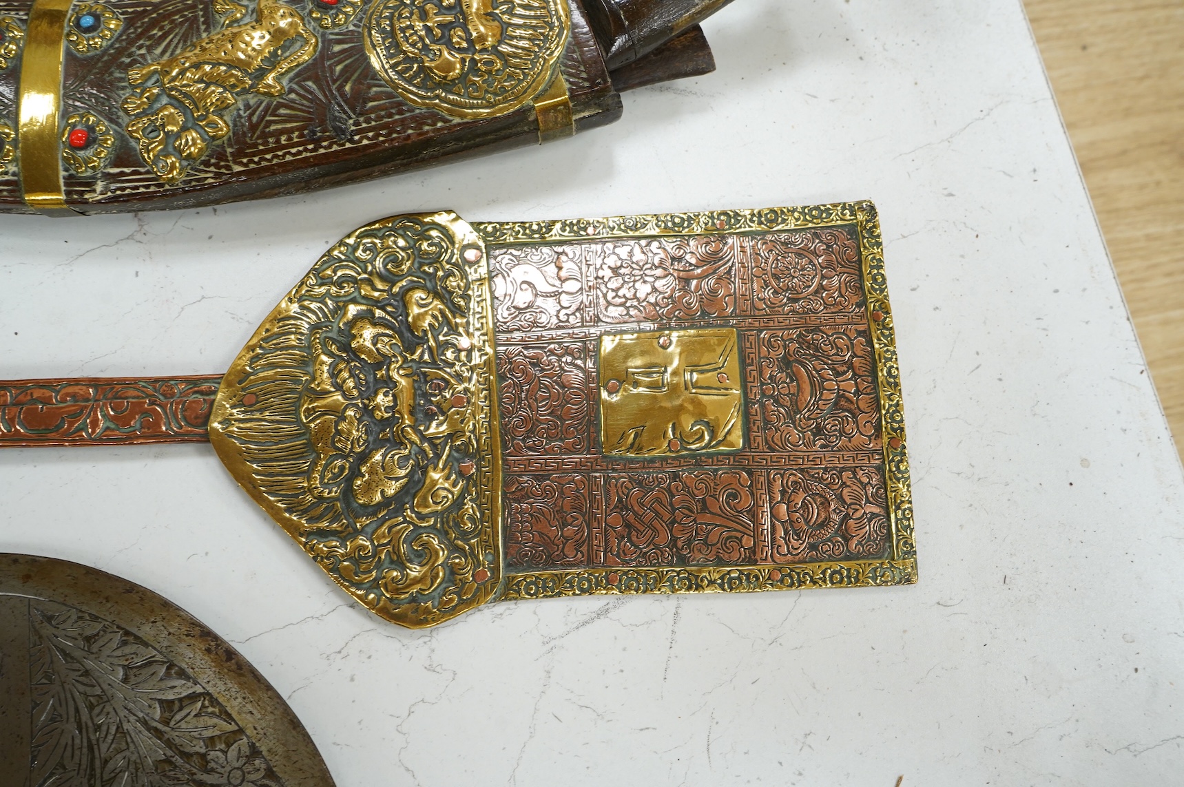 A decorative Indian axe, the large head inlaid with brass Hindu figures, together with a brass mounted North Indian kukri, another similar knife with bone handle, and a large shovel-shaped copper and brass item possibly